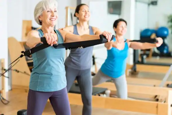 Toning Arms After 60: Empowering Womens Fitness Through Effective Weight Training 2 older woman doing weight training Devizes and resistance in the gym to tone upper arms