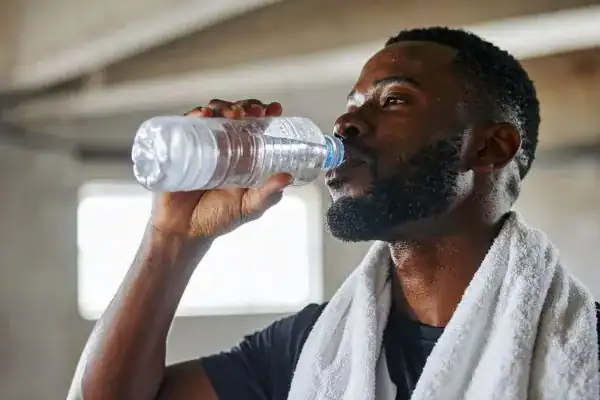 Image of man drinking water to improve hydration Devizes after work out.